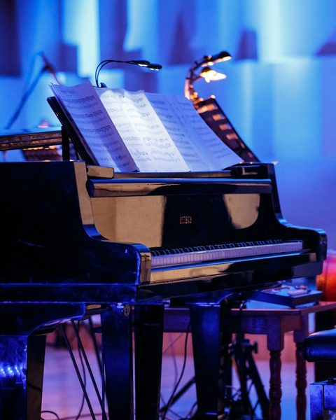 Pian de concert pe o scenă luminată în albastru